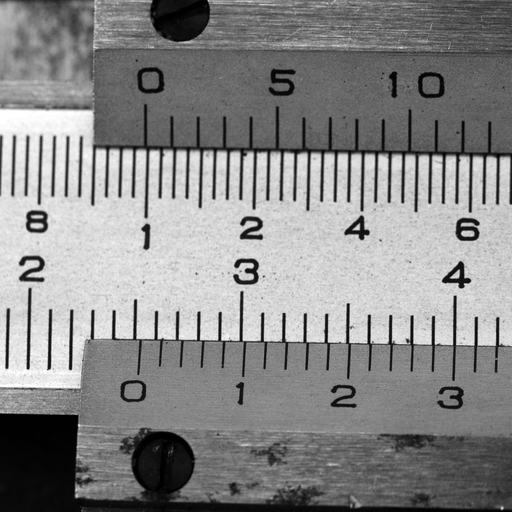 Macro photograph of a vernier caliper reading 25.3 millimetres: two engraved scales sliding against each other.